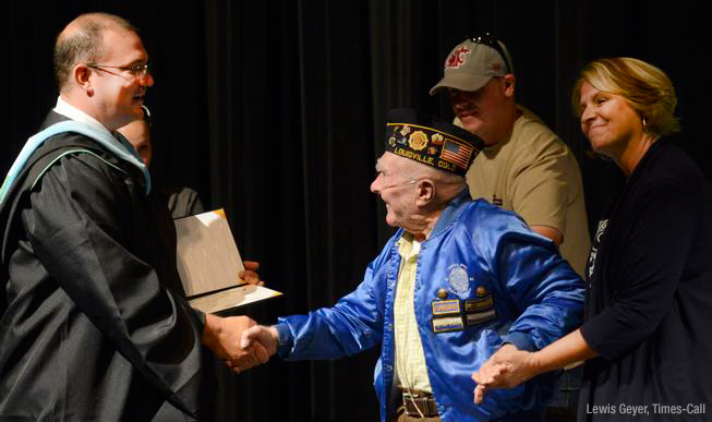 Erick Finnestead presenting WWII vet Henry Werner with high school diploma